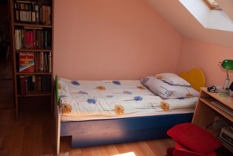 バダチョニトマイにあるKincsem Apartmanの本棚付きの部屋の小さなベッド1台