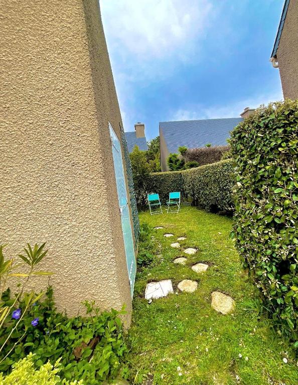 2 chaises assises dans une cour à côté d'un bâtiment dans l'établissement Refuge des Sables Marins, à Barneville-Carteret