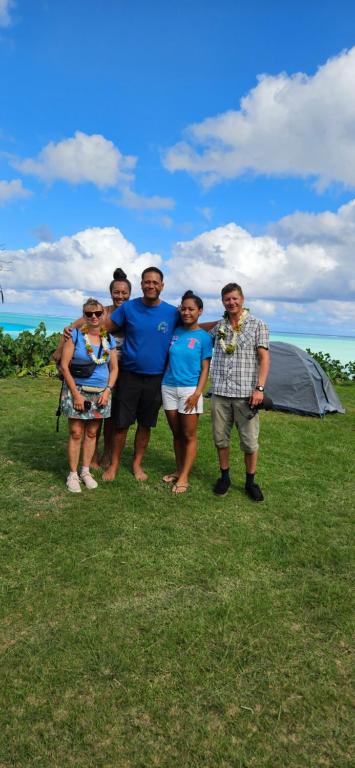 a group of people standing in a field with an umbrella at Taria Camping in Te-Fare-Arii