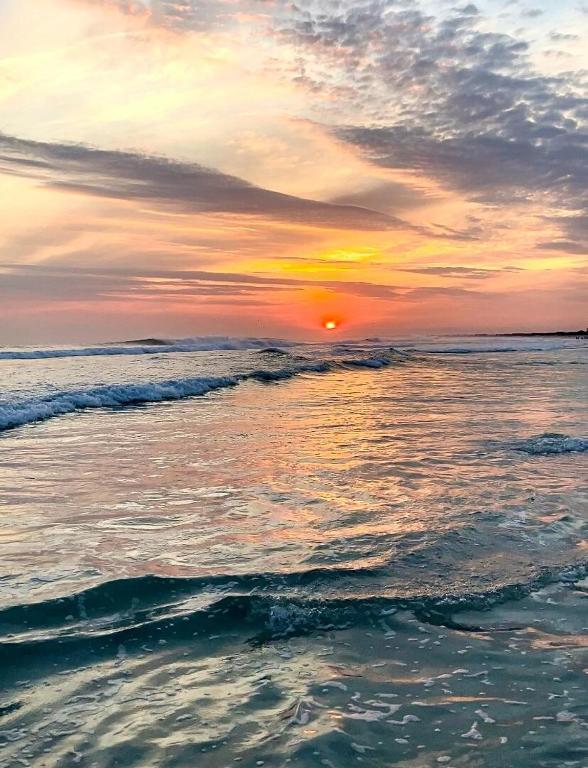 a sunset on the beach with the ocean at Recanto no Caribe in Arraial do Cabo