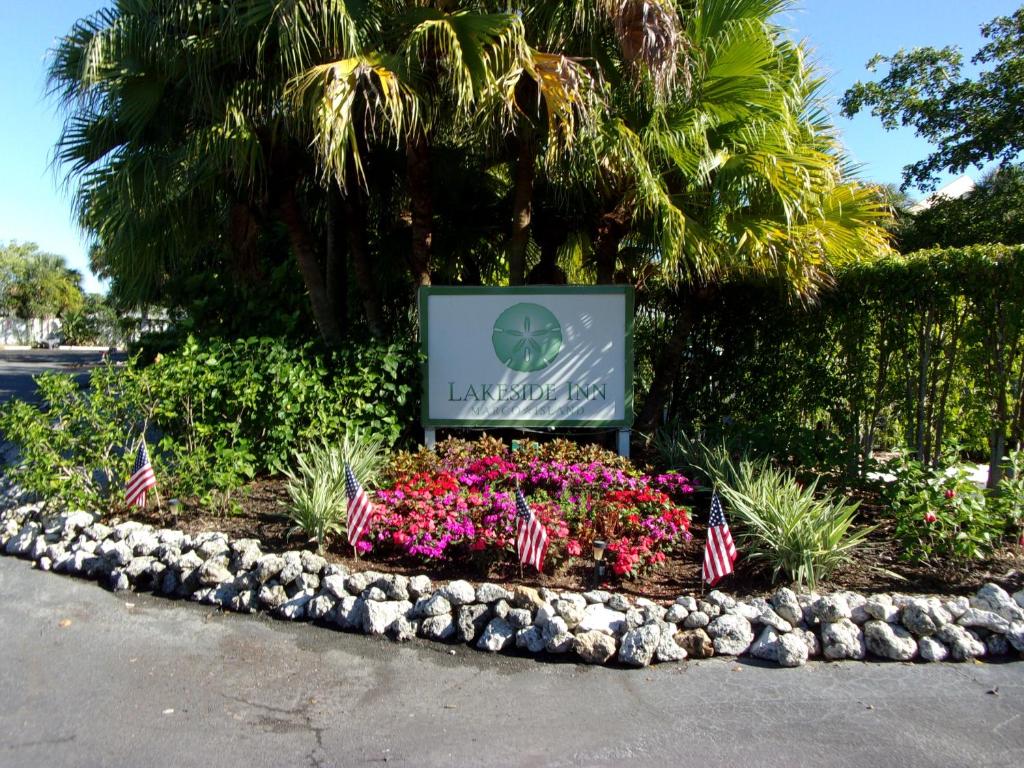 a sign in a flower bed with american flags at Marco Island Lakeside Inn in Marco Island