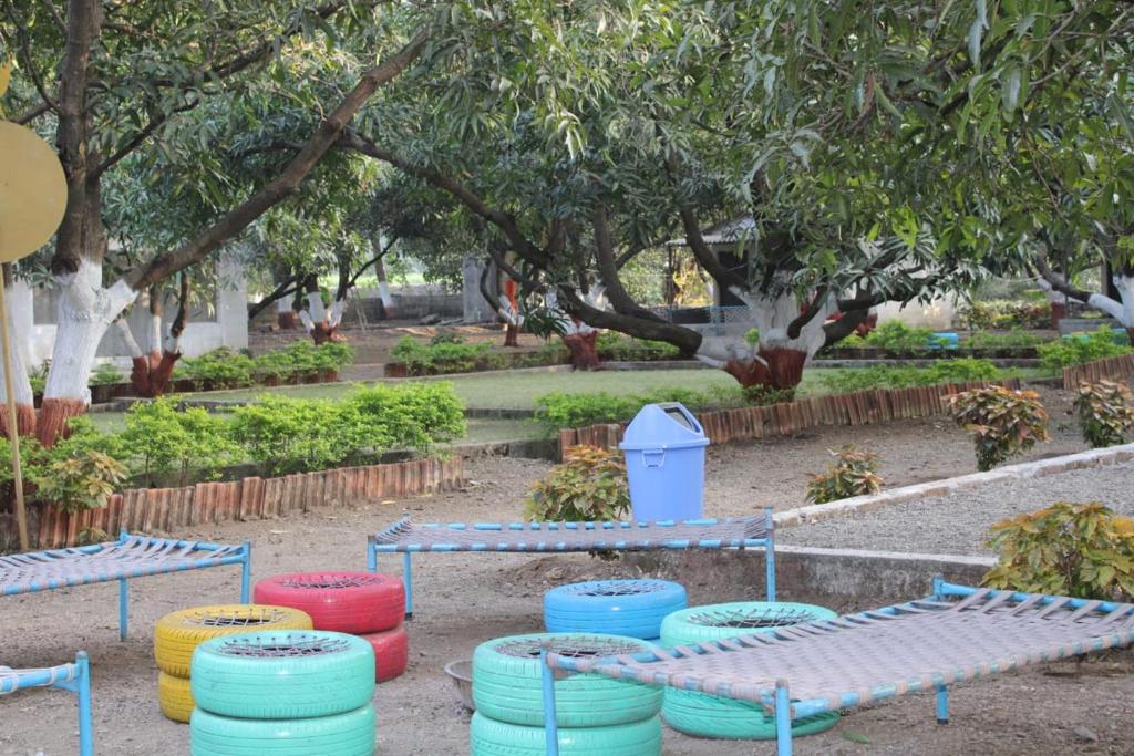 um parque com mesas, cadeiras e árvores coloridas em Gir Enjoy Forest Resort em Sasan Gir