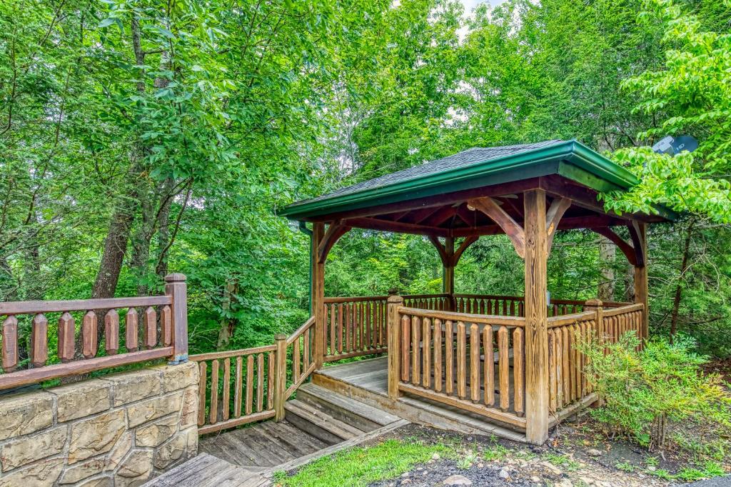 a wooden gazebo with a green roof at Mountain Charm- Hot Tub, Game Room, Theater Room, free Attraction Tickets!!! in Sevierville