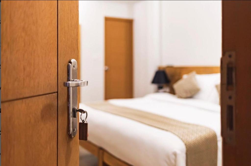 a bedroom with a bed and ajar door with a bed at Suffix Retreat - Stay, Dive & Explore Fuvahmulah in Fuvahmulah