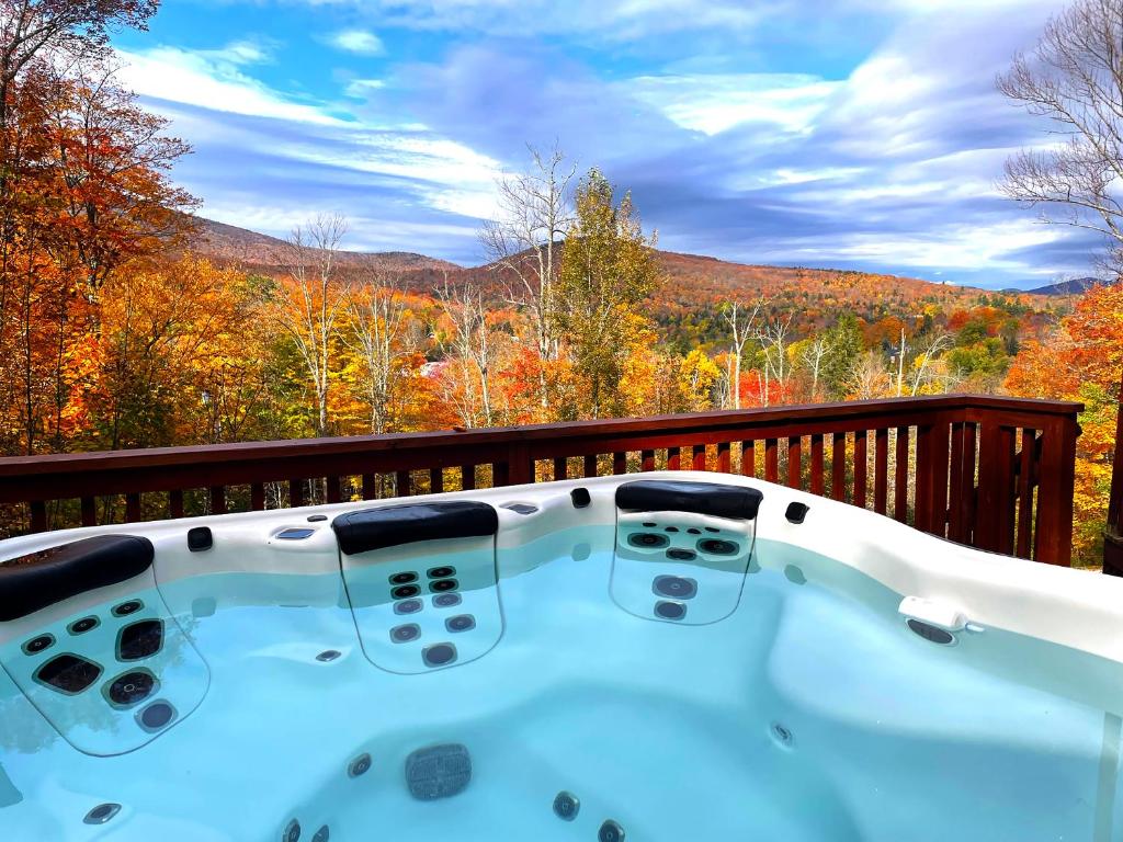 a jacuzzi tub on a deck with fall foliage at Beartopia- Hot Tub, Views, 2 Primary Suites! in Killington