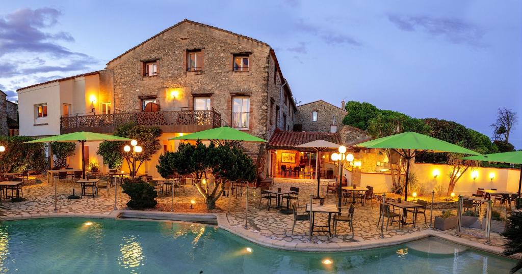 un hotel con piscina frente a un edificio en Auberge Du Roua, en Argelès-sur-Mer