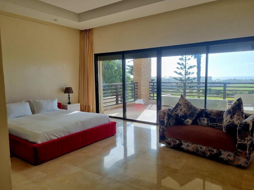 a bedroom with a bed and a chair and a balcony at Villa Mazagan de luxe 6 chambres face mer 1000m2 in El Jadida