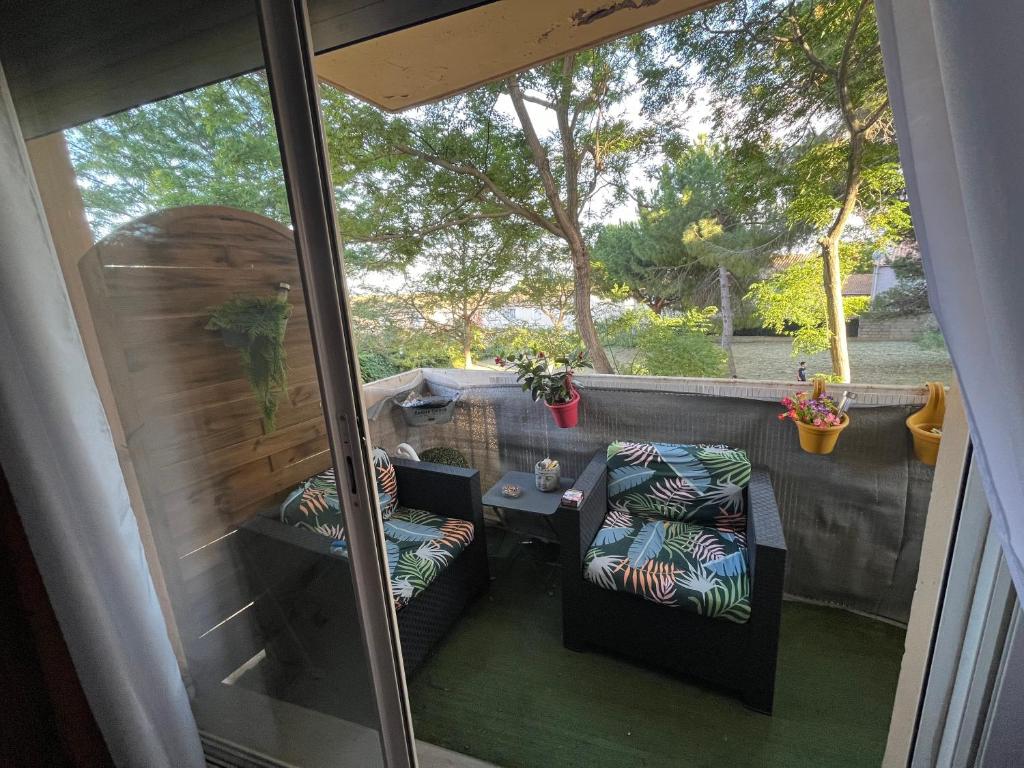 un patio avec deux chaises et une table sur un balcon dans l'établissement Béziers 2 chambres résidence avec parking privatif, à Béziers