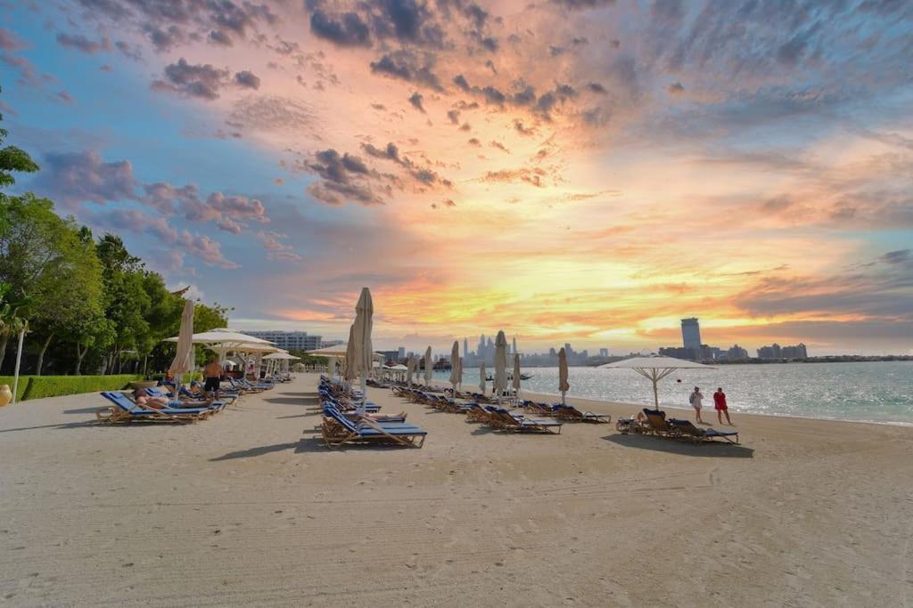 una spiaggia con un sacco di sedie e ombrelloni di FIRST CLASS 1BR Anantara The Palm Hotel a Dubai