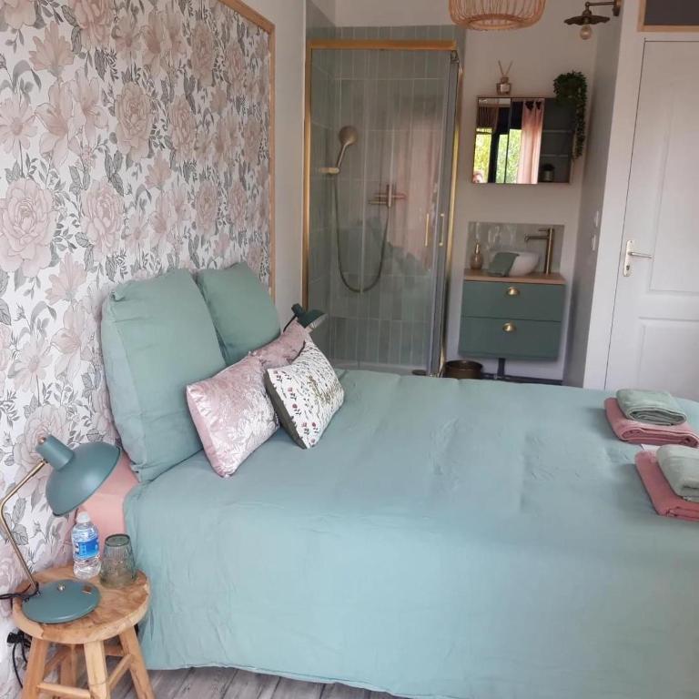 - une chambre dotée d'un grand lit bleu avec des oreillers dans l'établissement Chambre Parenthèse Cosy et institut, à Neufmarché