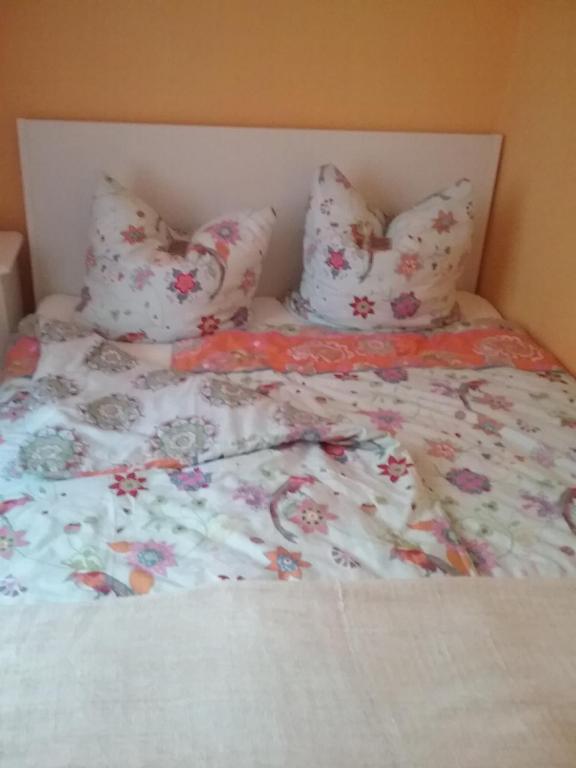 a bed with a floral comforter and pillows at Ferienwohnung im Kapitänsgarten in Prerow in Prerow