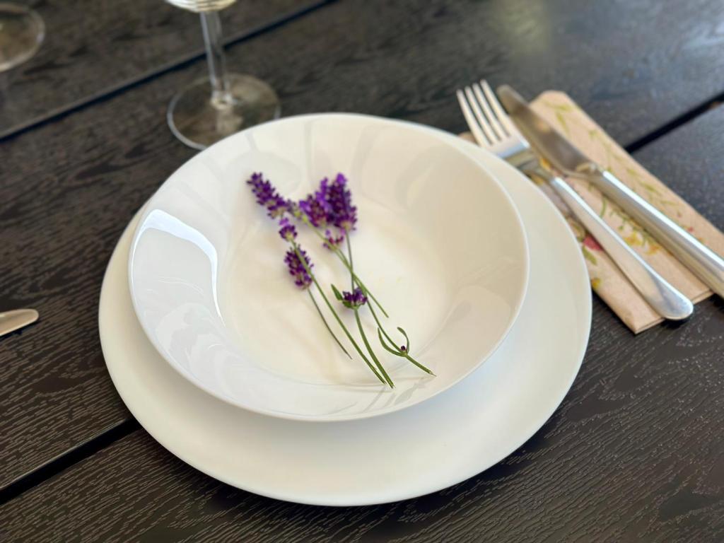 White dinnerware set with lavender sprig in bowl, dark wood table and silverware