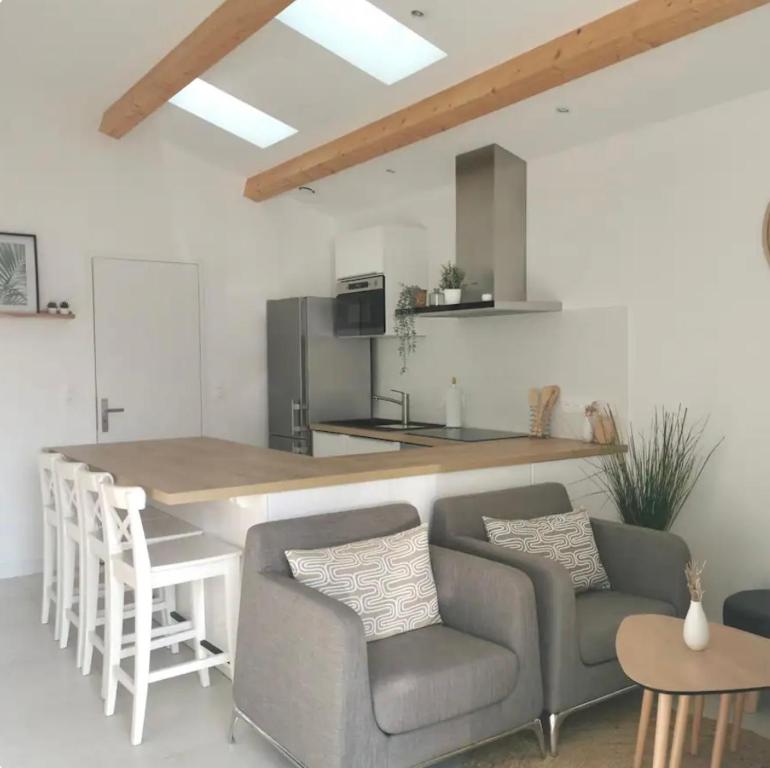 - une cuisine avec un bar avec des chaises et une table dans l'établissement Le cottage patio, à Ferrières