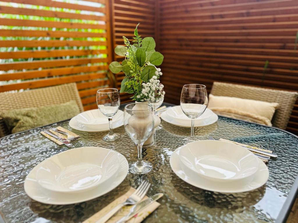 Close-up of glass patio table set with white plates, wine glasses and a green centerpiece.