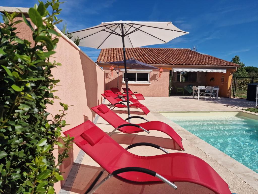 a row of red chairs and an umbrella next to a pool at La grange des vignes in Pomport