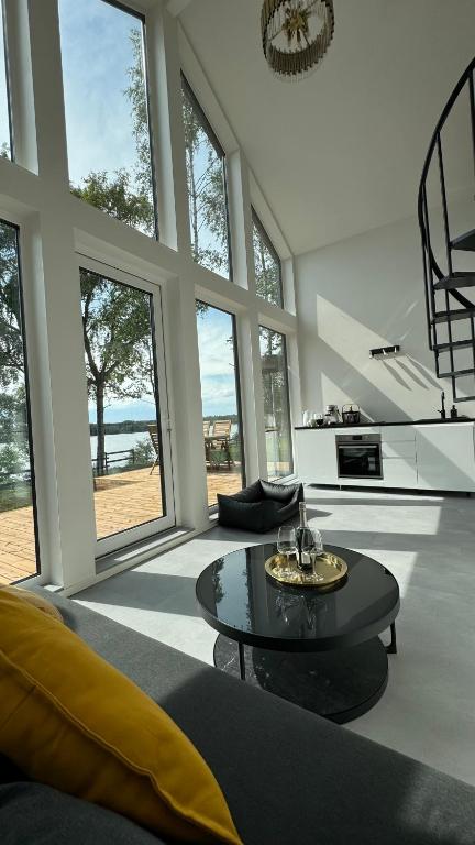 a living room with a table and large windows at GET WILD brīvdienu māja in Dzelmes