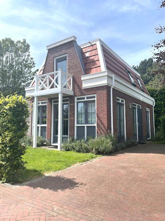 a red brick house with a white balcony on it at Tulp en Zee in Noordwijk