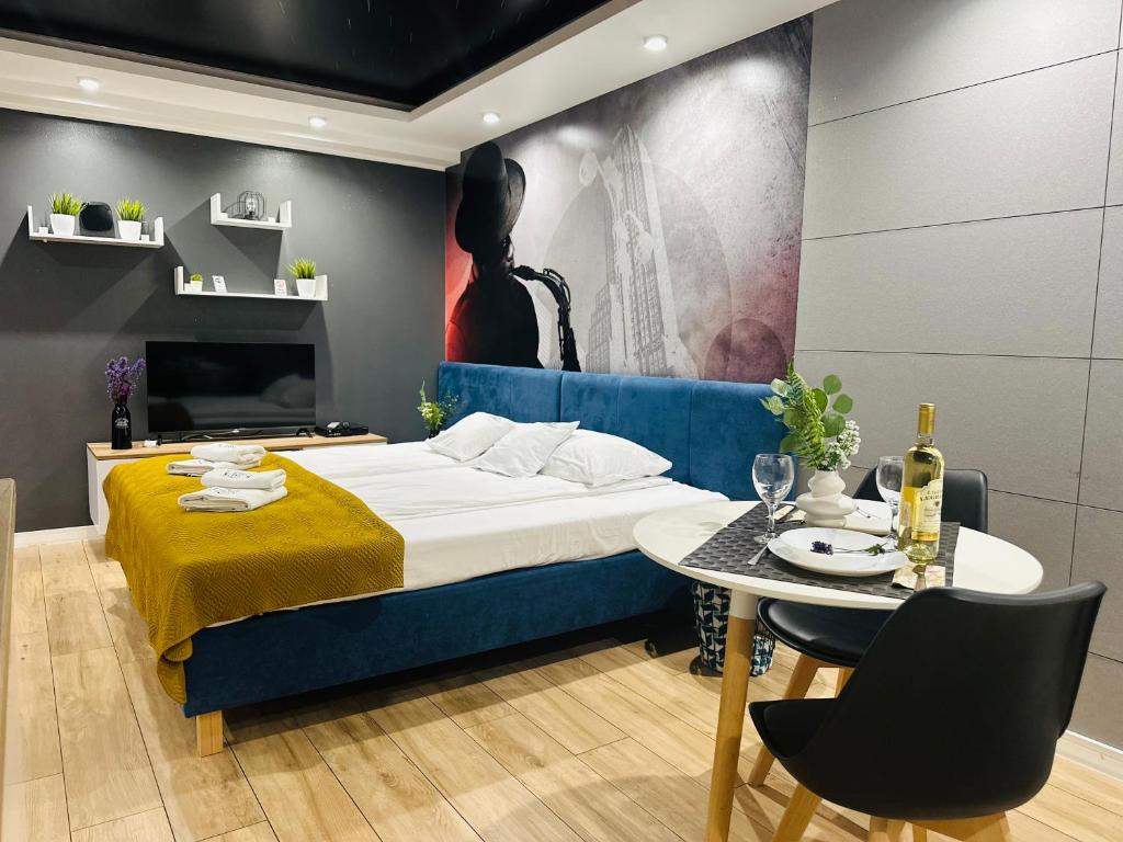 Stylish hotel room with blue upholstered bed, mustard throw, dining table set with wine