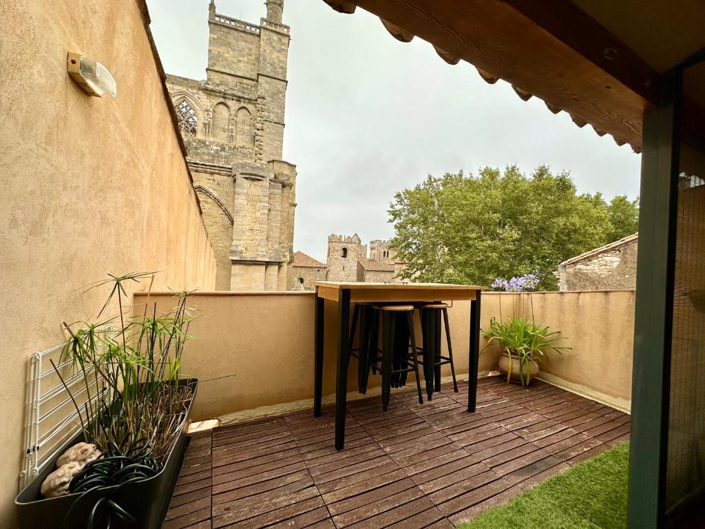 a balcony with a table and a view of a church at Trésors de la Cathédrale, Maison de Ville sur 4 niveaux in Narbonne