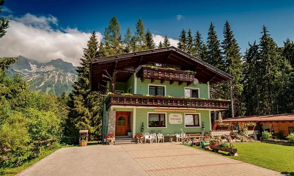 una casa verde con tavoli e sedie di fronte di Haus Petersmann a Ramsau am Dachstein