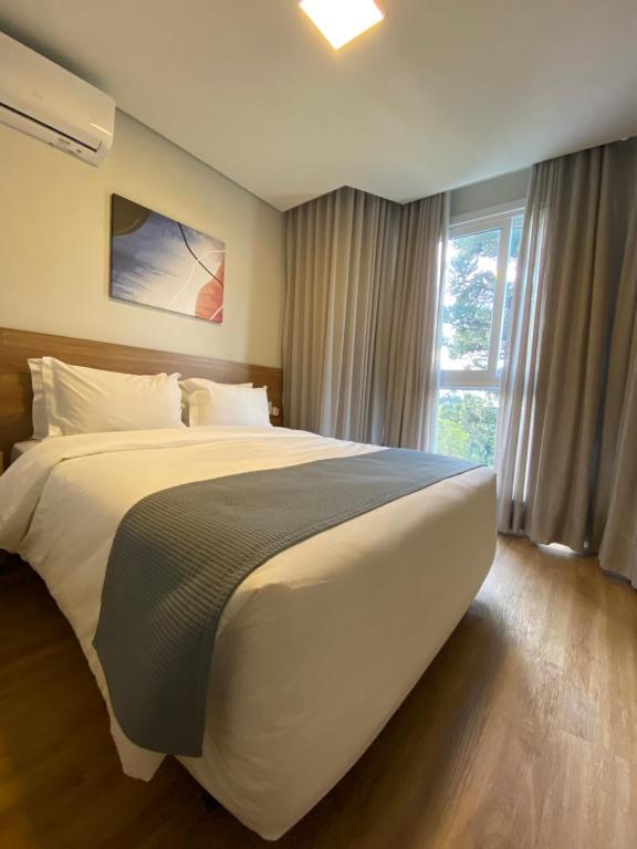 een groot wit bed in een slaapkamer met een raam bij Lindo flat no Serra Class in Canela