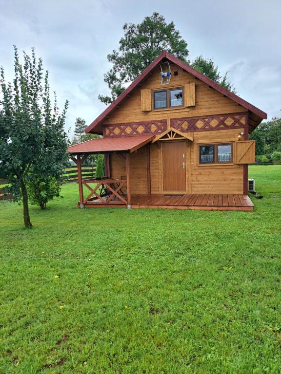 a large wooden cabin in a field of green grass at Osada Drzonek in Ludomy
