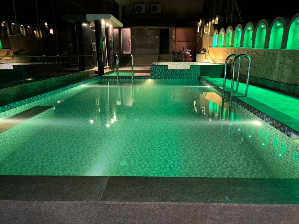 a swimming pool at night with green lights at Hotel Royale Palace in Mount Ābu