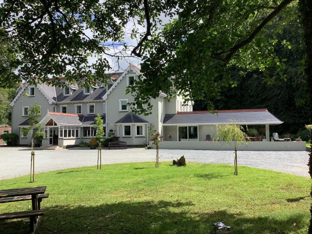 a large white house with a dog sitting in the grass at Gleann Fia Country House in Killarney