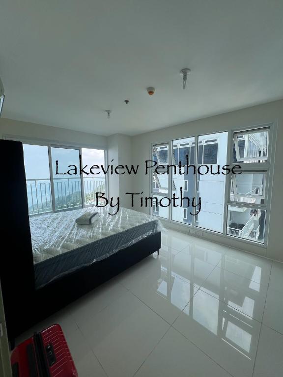a living room with a bed and a large window at Lakeview Penthouse by Timothy in Tagaytay