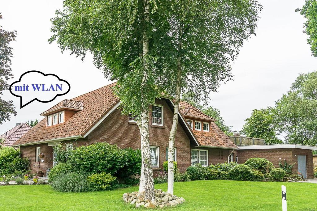 una casa con un árbol delante en Ferienwohnung Tammen, en Westoverledingen