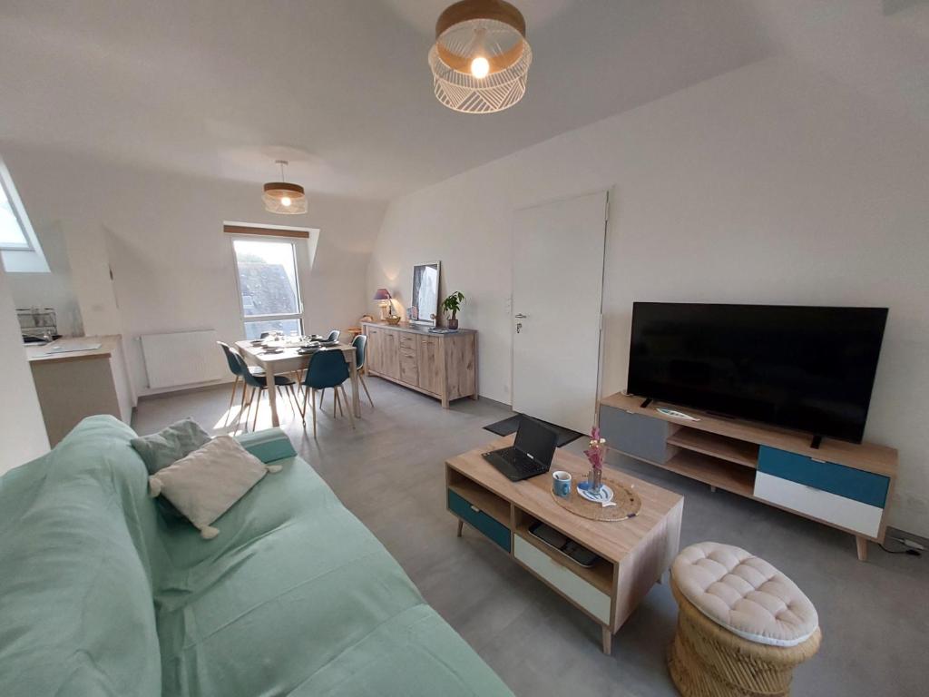 un salon avec un canapé vert et une télévision à écran plat dans l'établissement Menhirs et plages Carnac, à Carnac