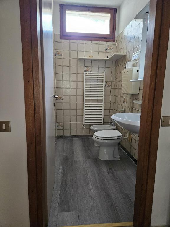 łazienka z toaletą, umywalką i oknem w obiekcie Villa a schiera raffinata con giardino w Lignano Sabbiadoro