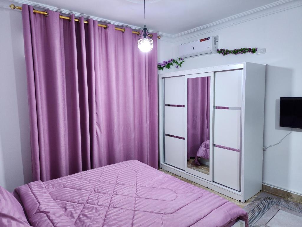 una camera da letto con tende viola e un letto con uno specchio di Salo StudioS ad Amman