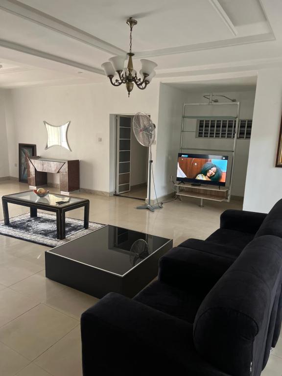 a living room with a black couch and a table at Apartment Three Oranges SH 75 E Nza Street Independence Layout Enugu in Mama