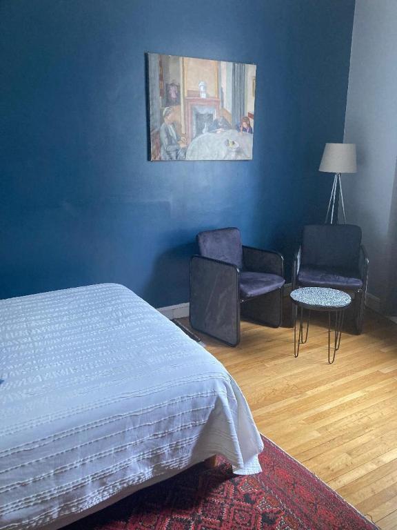 - une chambre avec un lit, des chaises et un mur bleu dans l'établissement Chambre d'hôtes La grotte de Voltaire, à Nantes