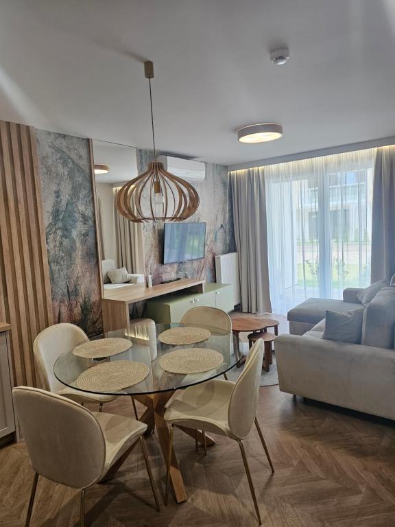 un salon avec une table, des chaises et un canapé dans l'établissement LUKSUSOWY APARTAMENT przy Plaży, à Grzybowo