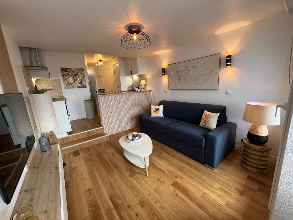 Una sala de estar con un sofá azul y una mesa. en Zen Studio Marina Deauville Vue Mer - Design Chic, en Deauville