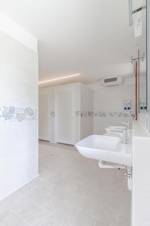 un bagno bianco con due lavandini e una vasca di AgriCamping Ca' Bodi a Cavallino-Treporti