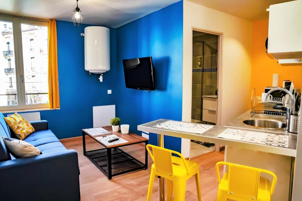 Il comprend une cuisine et un salon avec des murs bleus et des chaises jaunes. dans l'établissement T2 Chic proche de la gare Châteaucreux, à Saint-Étienne