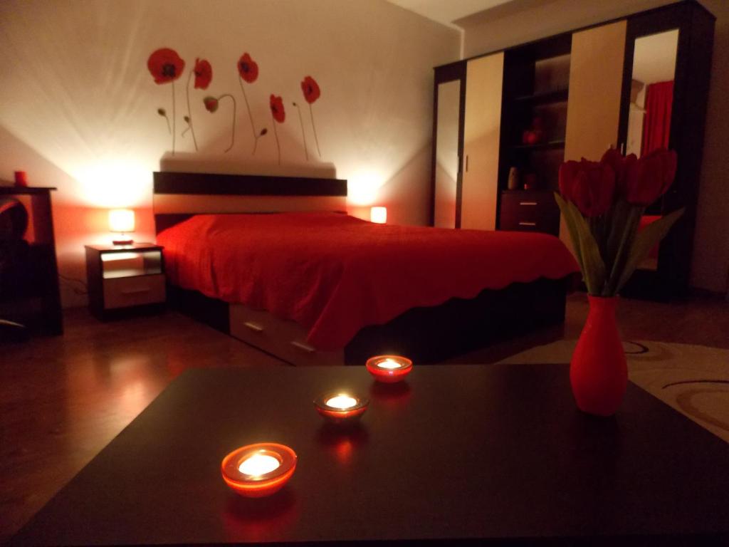 1 dormitorio con 1 cama con velas y flores rojas en Studio Lujerului Bucuresti, en Bucarest