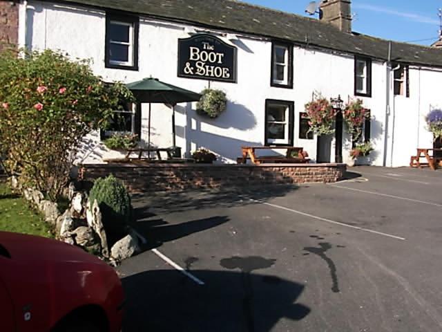 un edificio con un letrero que lee raíces y tiendas en Boot & Shoe Inn, en Greystoke