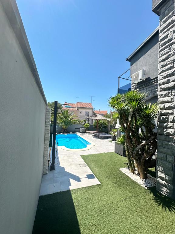 a backyard with a swimming pool and grass at Apartmani Vernissage in Biograd na Moru