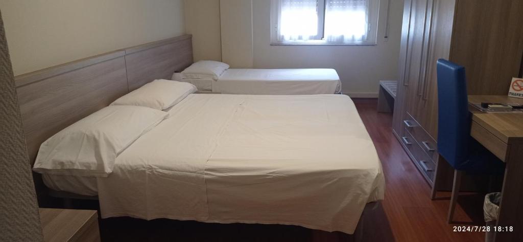 two beds in a small room with a window at Hotel Calypso in Ventimiglia