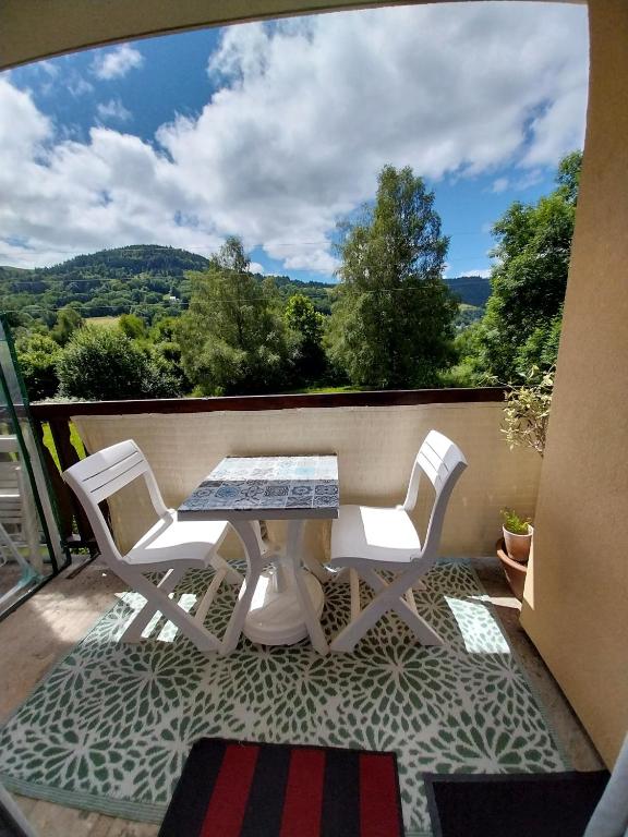 une table et des chaises sur un balcon avec vue dans l'établissement Studio La Bourboule, à La Bourboule