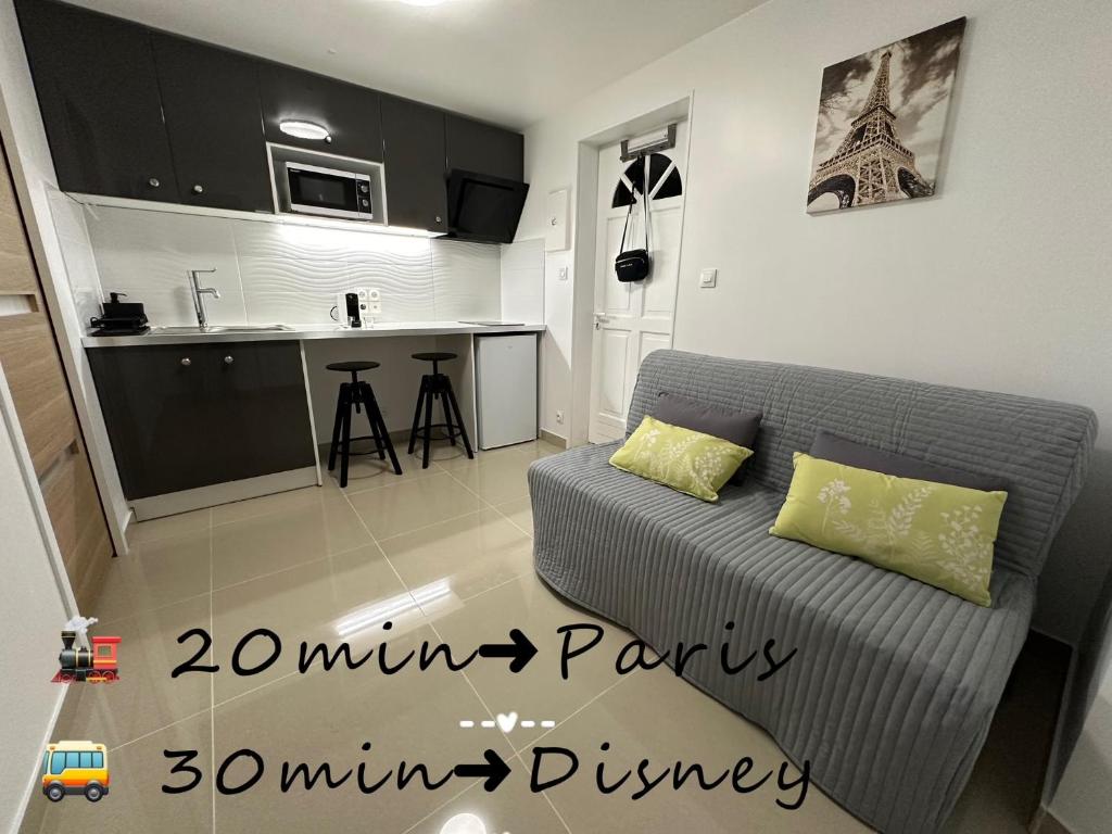un salon avec un canapé et une cuisine dans l'établissement Tranquillité près de Disney: Studio Cozy à Meaux, à Meaux