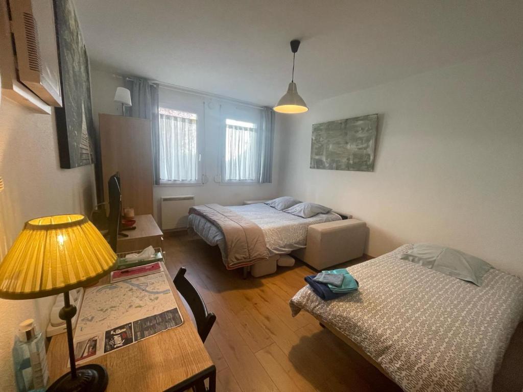 une chambre avec deux lits et une table avec une lampe dans l'établissement Studio Cozy centre ville Chalon-sur-Saône, à Chalon-sur-Saône