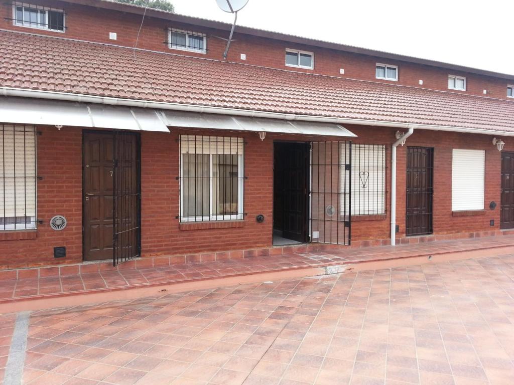 een gebouw van rode baksteen met deuren en ramen bij MaJoMi Toninas in Las Toninas