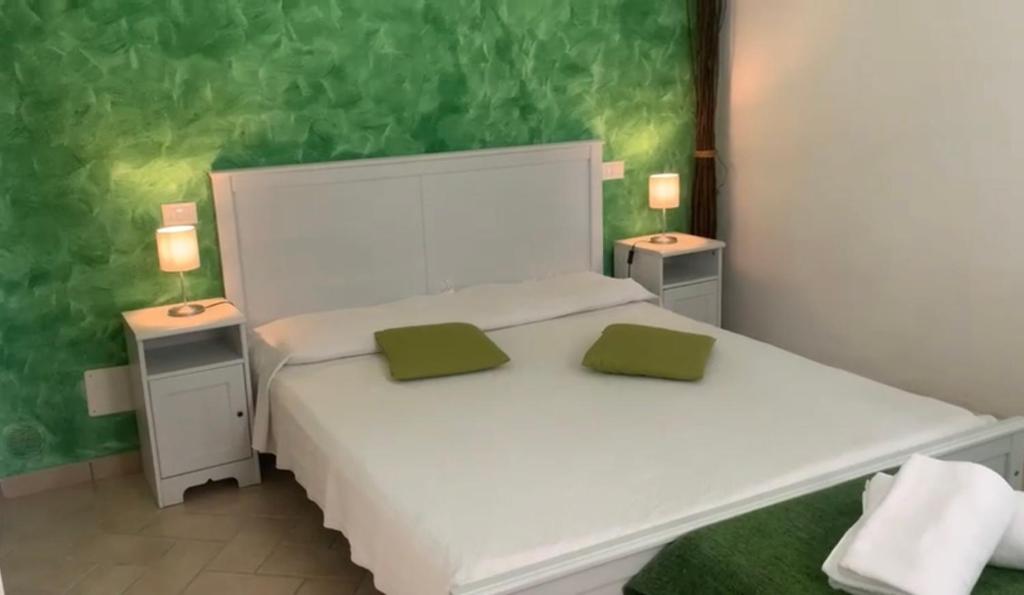 Una cama blanca con dos almohadas verdes encima. en B&B Campagna Casagrande, en Recco