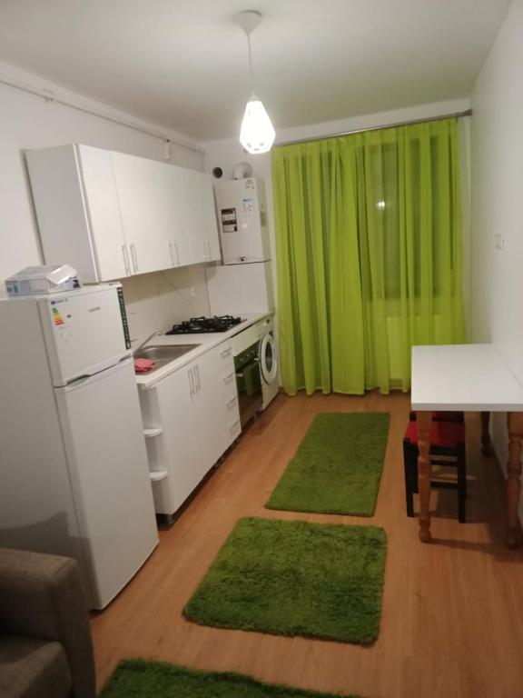 a kitchen with green curtains and a table with green rugs at Apartament luxury in Floreşti