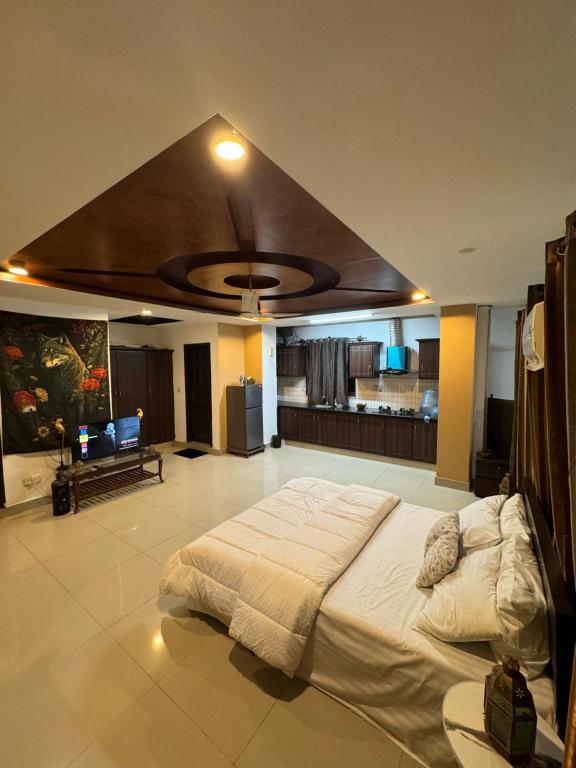 a bedroom with a large bed with a ceiling at Condo In Islamabad in Islamabad